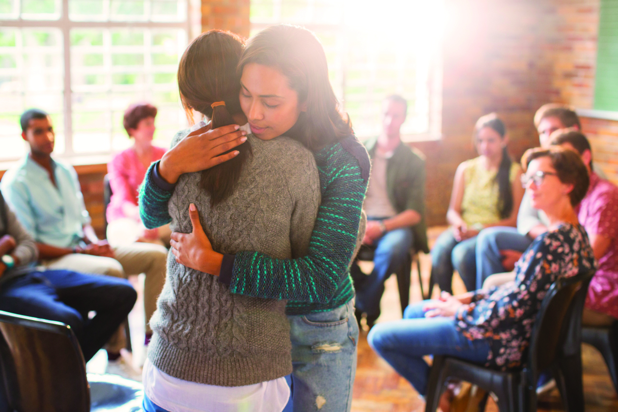 photo of a support group with two people hugging